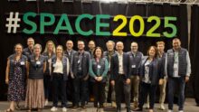 Un groupe de personnes pose devant une enseigne du Space 2025
