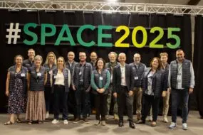 Un groupe de personnes pose devant une enseigne du Space 2025