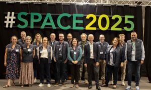 Un groupe de personnes pose devant une enseigne du Space 2025