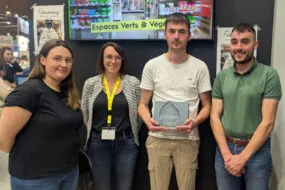 Un groupe de personne dont un tient un trophée dans ses mains