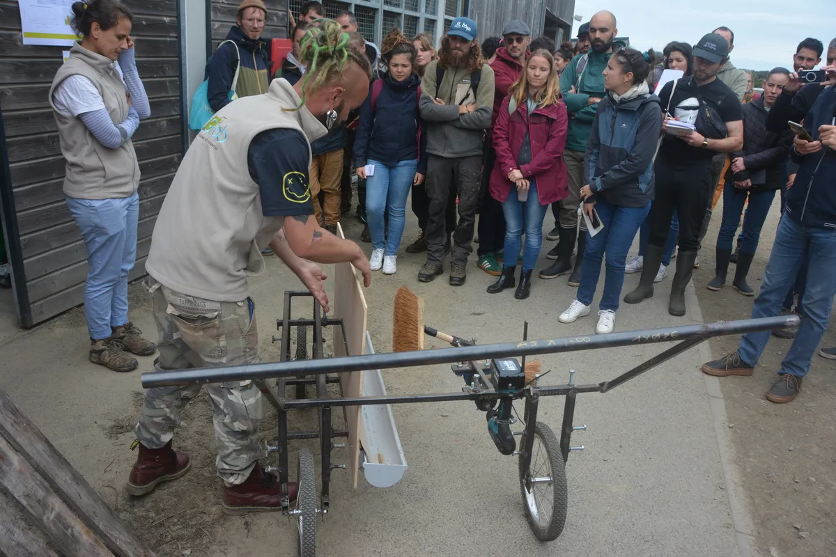 Un groupe de personne devant une balayeuse autoconstruite pour la culture maraichère - Illustration Un chasse-doryphore fait maison