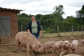 Une femme dans un enclos avec une truie et ses porcelets