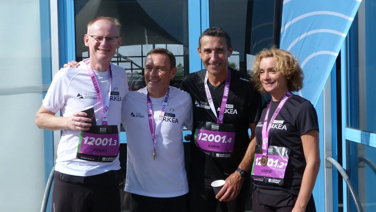 Trois hommes et une femme souriants avec des médailles autour du coup à l'arrivée d'une course