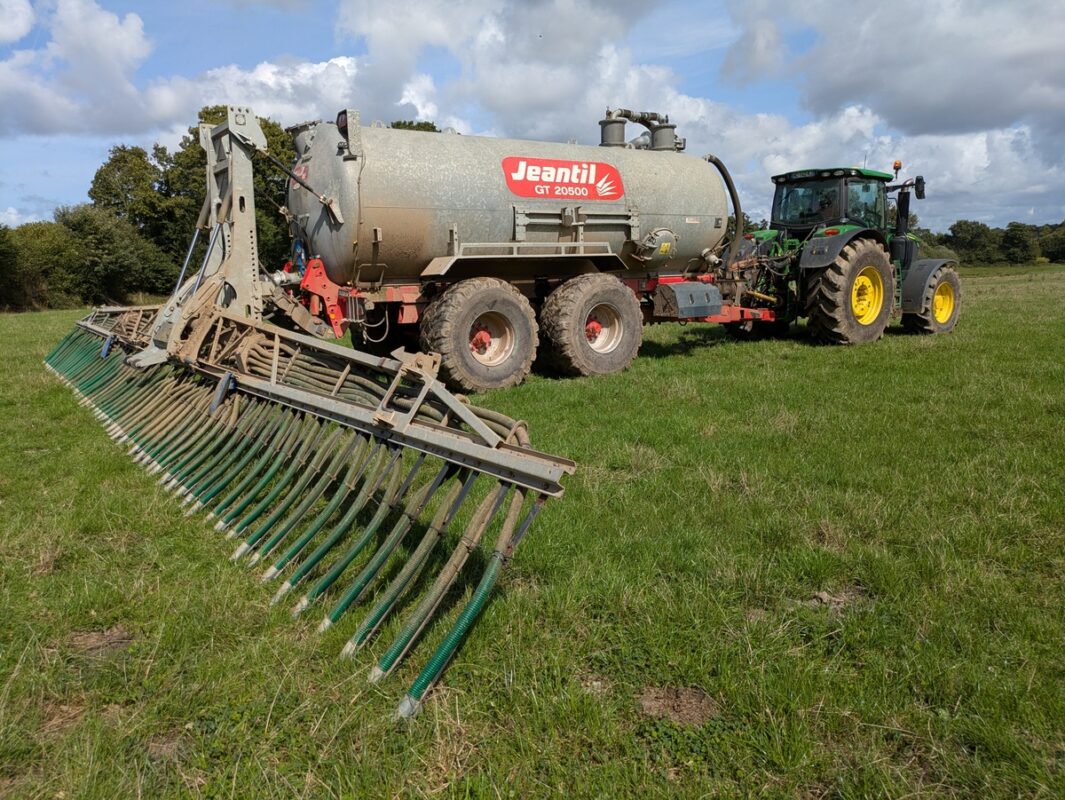 Un tracteur au champ avec une tonne à lisier équipée d'une rampe à patin