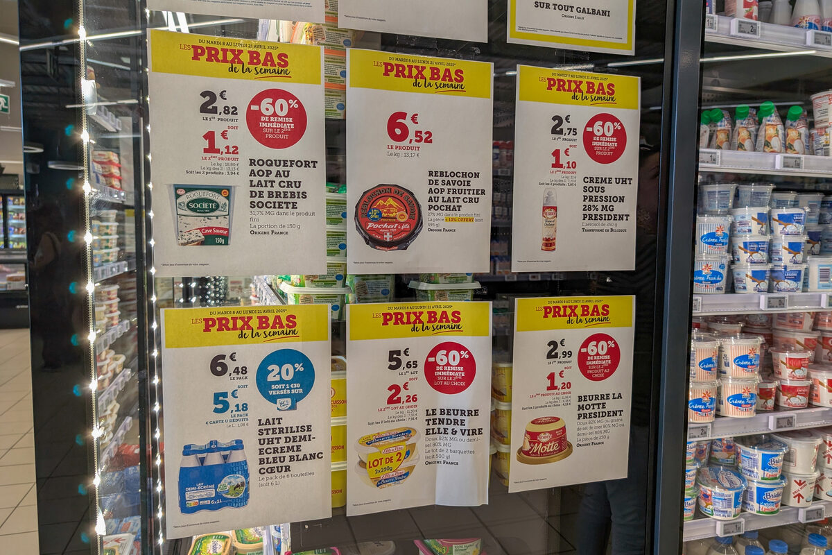 Des affichettes de promotions sur les produits laitiers collées sur la porte d'un réfrigérateur de grande surface - Illustration Egalim à l’épreuve