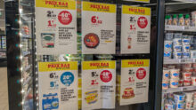 Des affichettes de promotions sur les produits laitiers collées sur la porte d'un réfrigérateur de grande surface