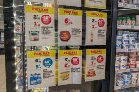 Des affichettes de promotions sur les produits laitiers collées sur la porte d'un réfrigérateur de grande surface