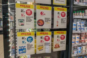 Des affichettes de promotions sur les produits laitiers collées sur la porte d'un réfrigérateur de grande surface
