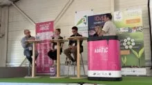 Trois personnes assises à des tables hautes et une autre derrière une banque d'accueil
