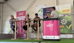 Trois personnes assises à des tables hautes et une autre derrière une banque d'accueil