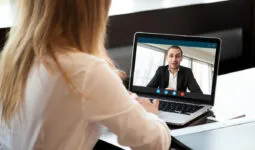 une femme de dos devant un écran d'ordinateur portable en visioconférence avec un homme