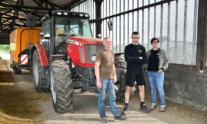 une femme et deux hommes devant un tracteur