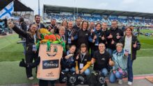 Un groupe de personne avec une mascotte d'Aucy dans un stade de rugby