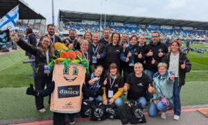 Un groupe de personne avec une mascotte d'Aucy dans un stade de rugby