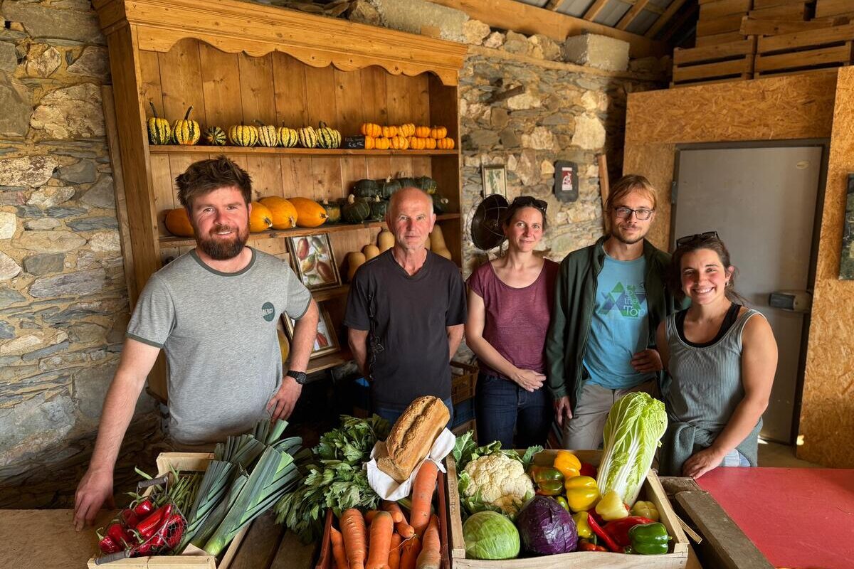 Un groupe de personne dans une pièce avec des murs de pierre, avec des cageots remplis de légumes posés sur une table devant eux - Illustration Deux Gaec accueillis sur sa ferme
