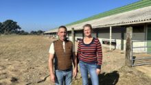 Un homme et une femme devant un bâtiment d'élevage de volailles