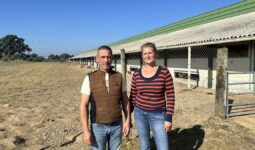 Un homme et une femme devant un bâtiment d'élevage de volailles