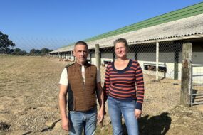 Un homme et une femme devant un bâtiment d'élevage de volailles