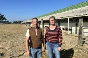 Un homme et une femme devant un bâtiment d'élevage de volailles