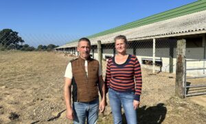 Un homme et une femme devant un bâtiment d'élevage de volailles