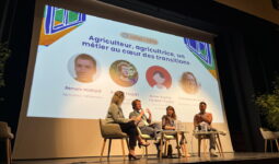 Quatre personnes sur une scène lors d'une conférence avec un grand écran derrière