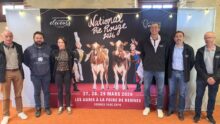 Des personnes posent devant une affiche du concours national bovin de race Pie Rouge