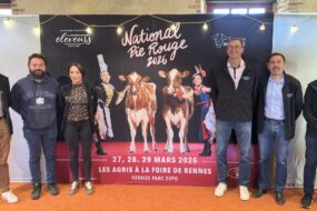 Des personnes posent devant une affiche du concours national bovin de race Pie Rouge