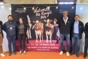 Des personnes posent devant une affiche du concours national bovin de race Pie Rouge