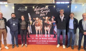Des personnes posent devant une affiche du concours national bovin de race Pie Rouge