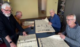 Quatre hommes feuillettent des journaux agricoles anciens