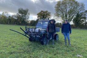deux hommes devant un SSV dans un pâturage