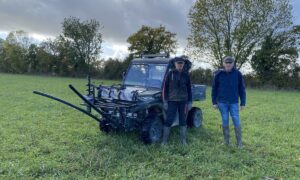 deux hommes devant un SSV dans un pâturage