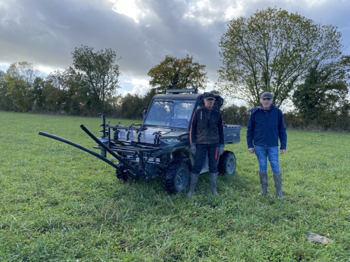 deux hommes devant un SSV dans un pâturage