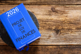 Un livre intitulé projet de loi de finances 2026 posé sur une table en bois