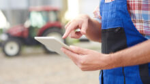 agriculteur dans une cour de ferme avec une tablette à la main