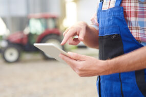 agriculteur dans une cour de ferme avec une tablette à la main