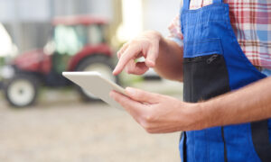 agriculteur dans une cour de ferme avec une tablette à la main