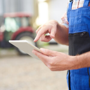agriculteur dans une cour de ferme avec une tablette à la main