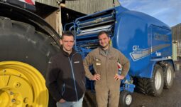 Deux personnes devant un tracteur et une presse pour round baler