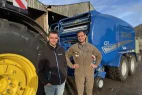 Deux personnes devant un tracteur et une presse pour round baler