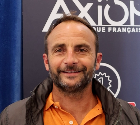 Portrait de Mickaël Guilloux devant une affiche Axiom