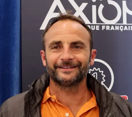 Portrait de Mickaël Guilloux devant une affiche Axiom
