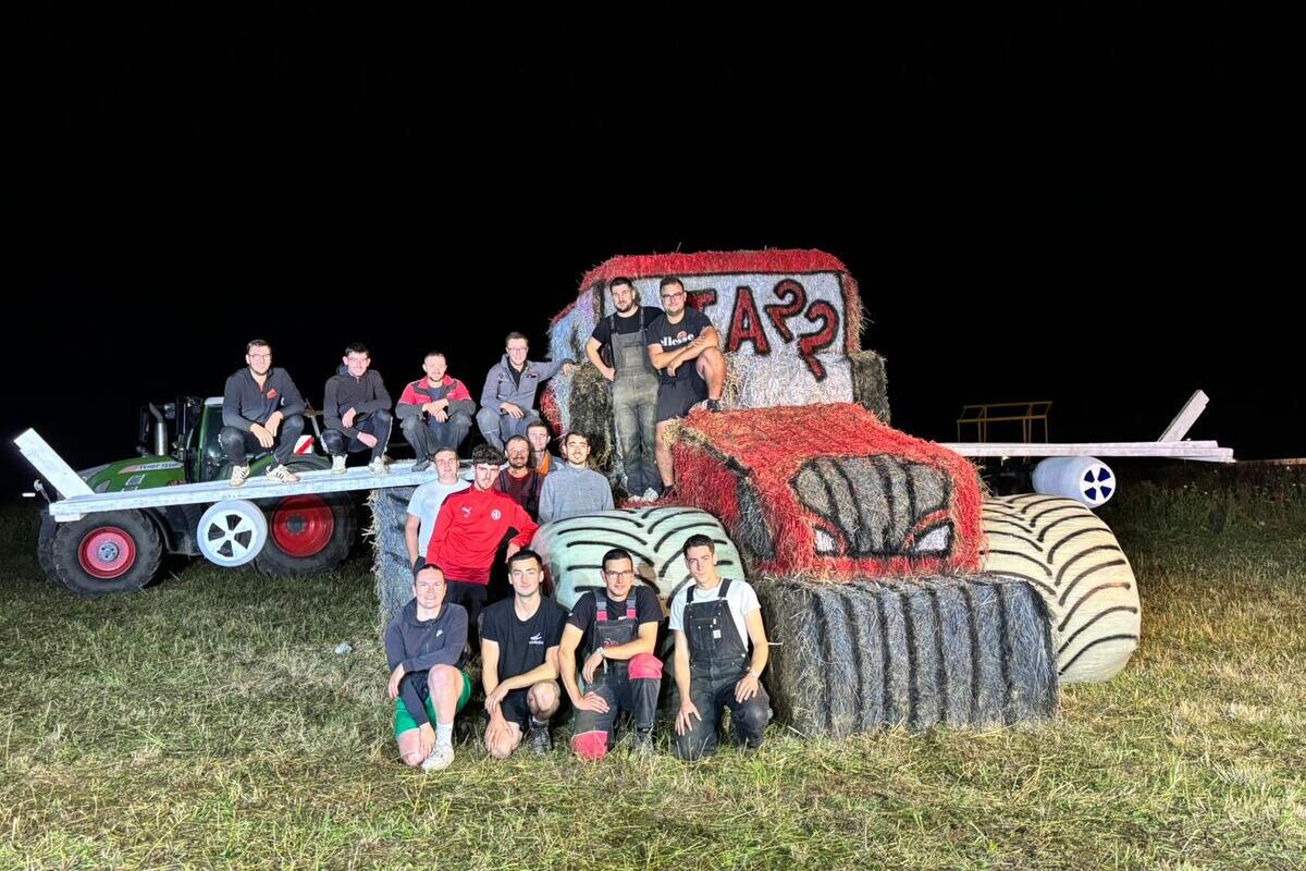 Des jeunes agriculteurs autour d'une structure de paille représentant un tracteur avec des ailes - Illustration Le tracteur ailé gagne le concours JA’stuce