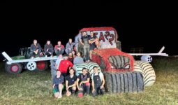 Des jeunes agriculteurs autour d'une structure de paille représentant un tracteur avec des ailes