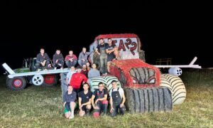 Des jeunes agriculteurs autour d'une structure de paille représentant un tracteur avec des ailes