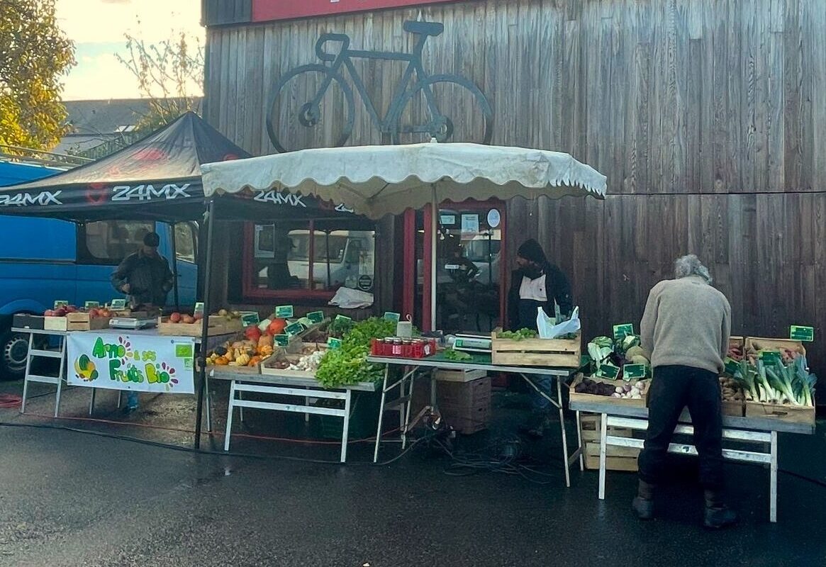 Étal de légumes sur un marché avec des personnes - Illustration La Conf’ organise son propre marché