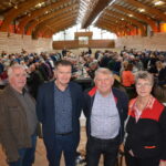 Quatre personnes dans une salle avec une assemblée derrière