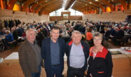 Quatre personnes dans une salle avec une assemblée derrière