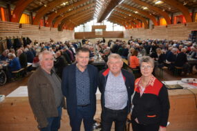 Quatre personnes dans une salle avec une assemblée derrière
