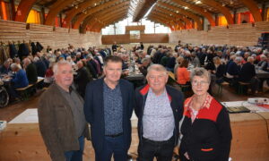 Quatre personnes dans une salle avec une assemblée derrière